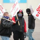 Masked strikers carry signs