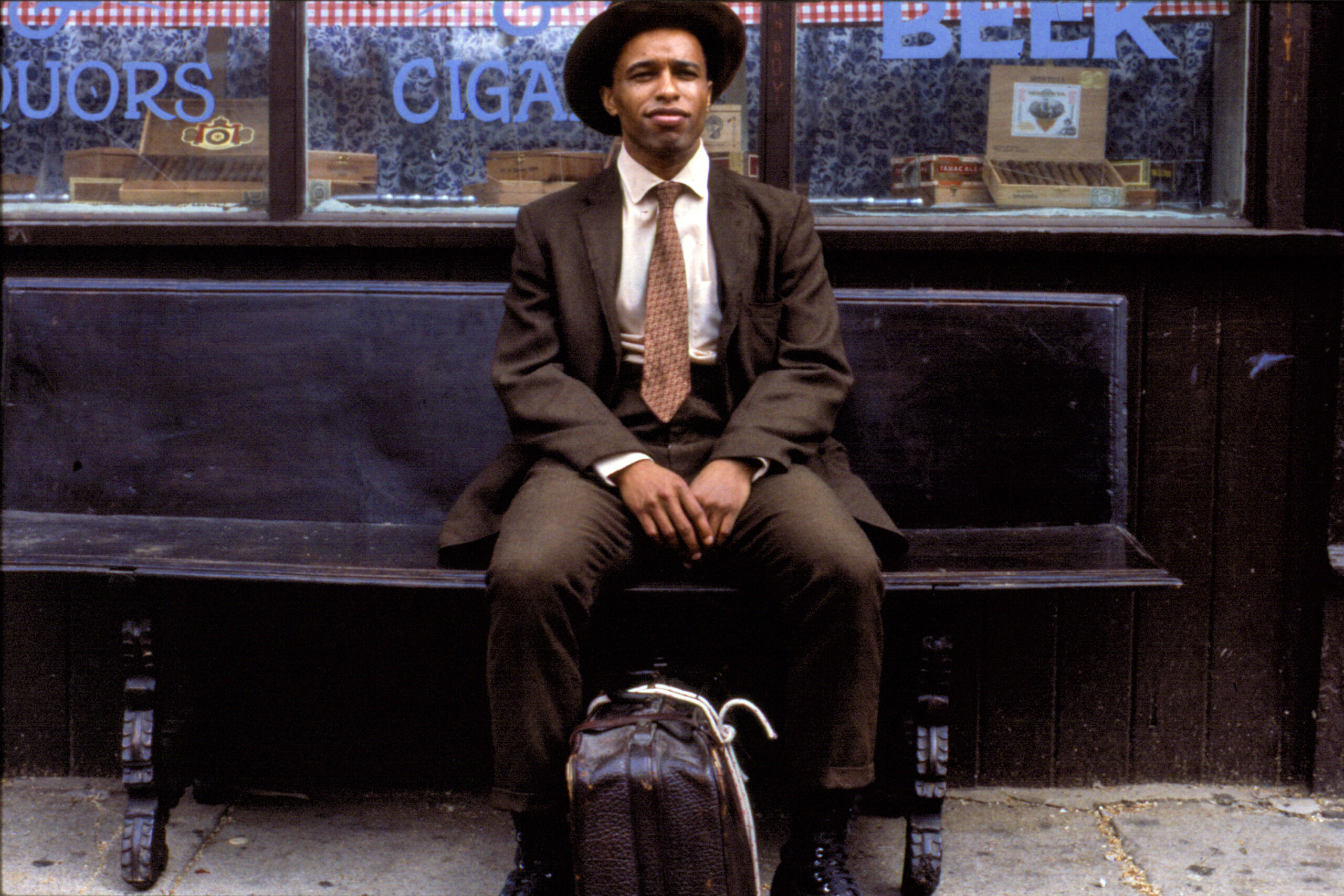 Suited up black man Frank Custer sits on bench