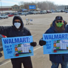 Men hold up fists and signs that say "WalMart say it ain't so!"