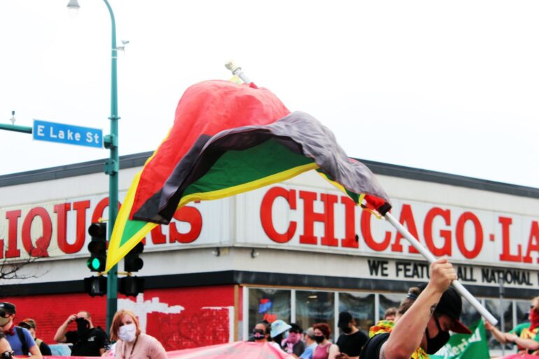 a a flag containing colors black, green, and yellow is waved in front of Chicago Lake Liquors on Lake St