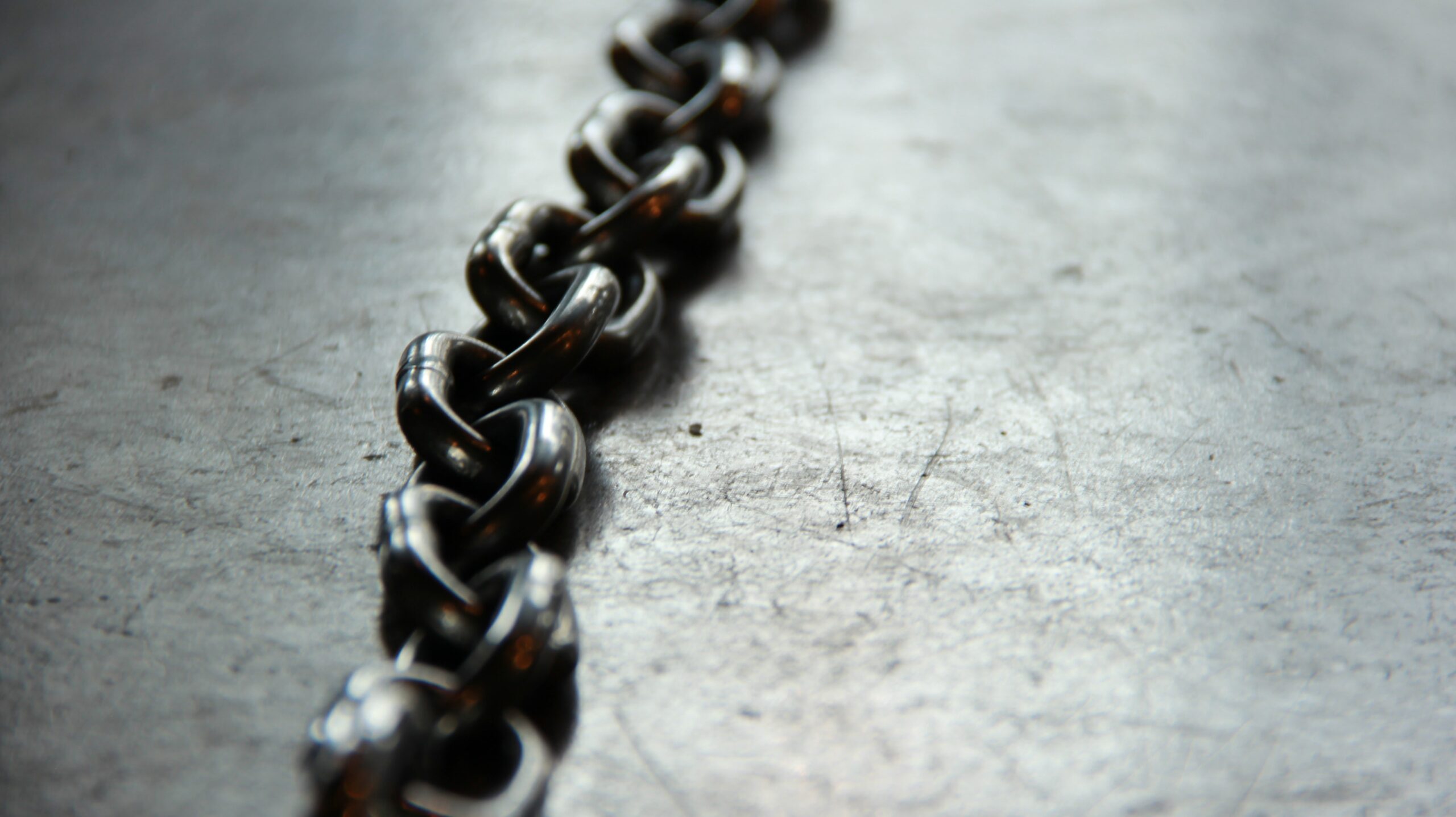 a line of steel chains lie on grey concrete ground