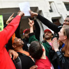close up of a crowd of smiling and happy people holding up a piece of paper