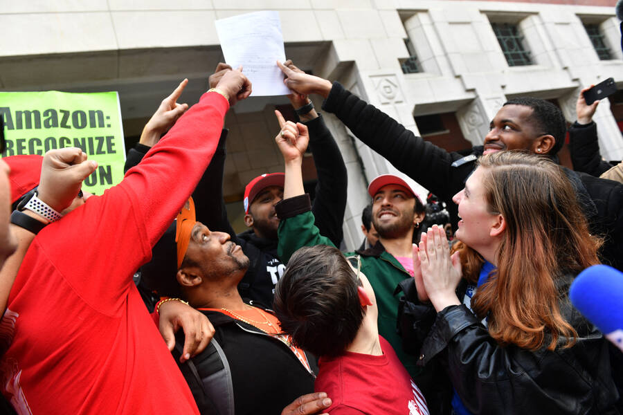 close up of a crowd of smiling and happy people holding up a piece of paper