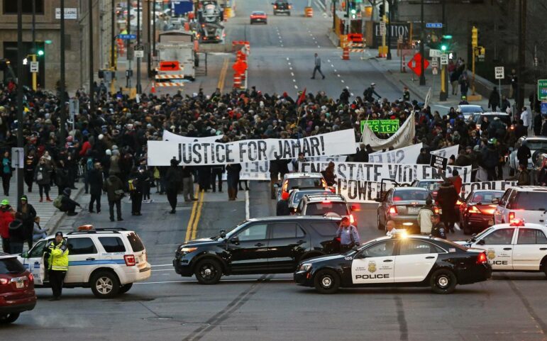 Protesters in Minneapolis hold up a banner that reads "Justice for Jamar!" made by Piotr Szyhalski.