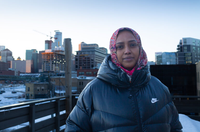 Khali Jame stands before the downtown Minneapolis skyline. 