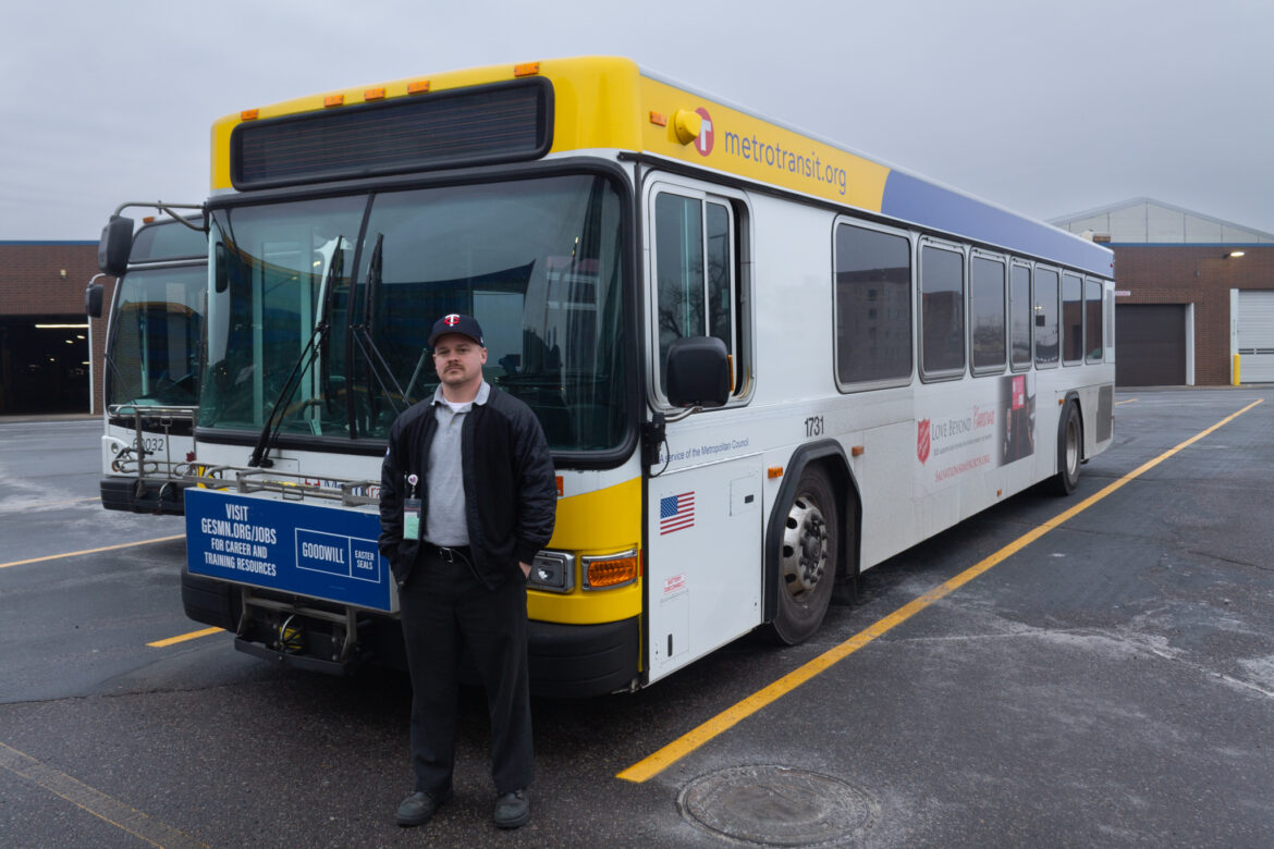 Adam Burch, bus operator, stands in front of a bus after a shift.
