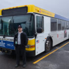 Adam Burch, bus operator, stands in front of a bus after a shift.