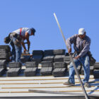 Two construction workers on the roof of a building.