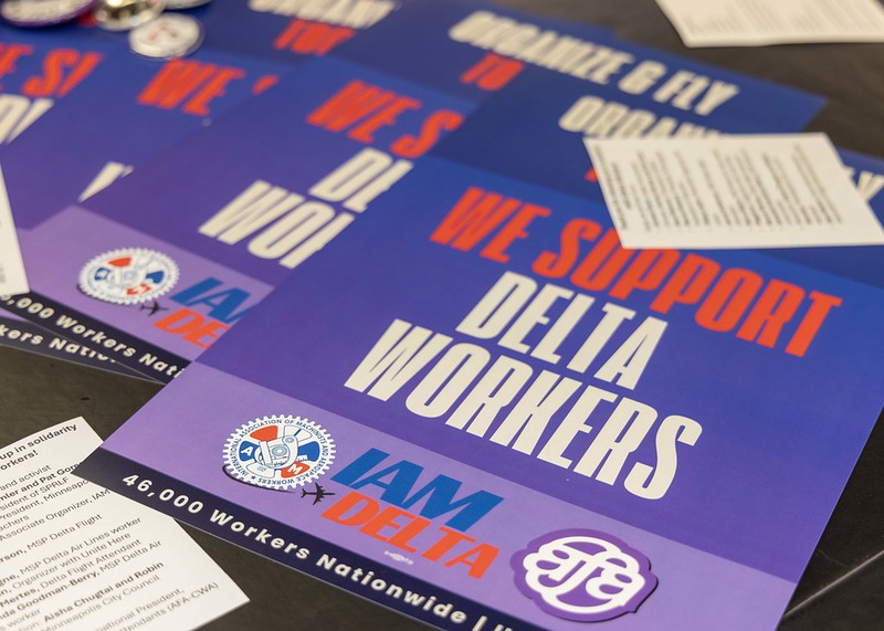 Purple posters with red and white text read "We support Delta Workers" With the IAM and AFA logos