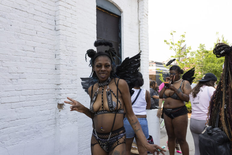 Lexi Collins, a local labor organizer, wears black feathered angel wings and throws a peace sign.