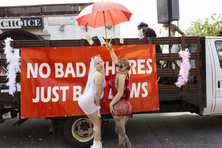 Two parade goers pose for a photo in front of the parade’s truck that reads, “No bad whores, just bad laws”.