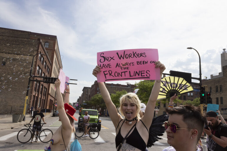 A marcher holds up a sign that reads, “Sex workers have always been on the frontlines”.