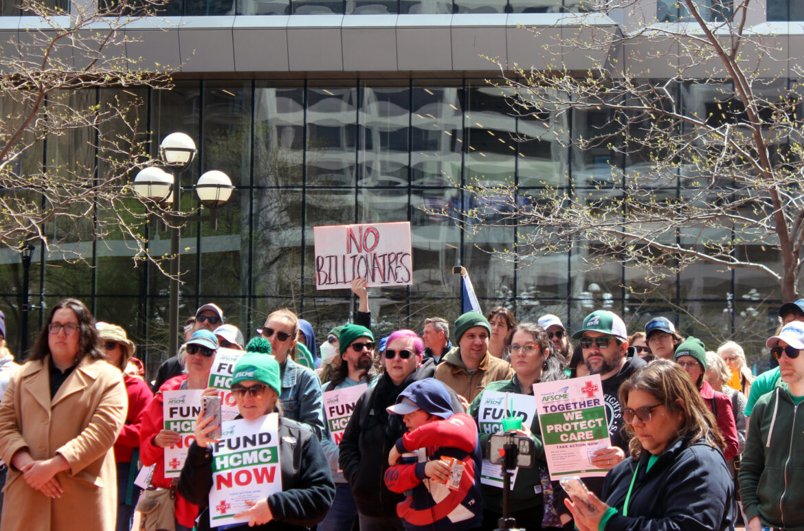 Public sector workers represented by AFSCME rally for May Day wearing green and holding up signs.